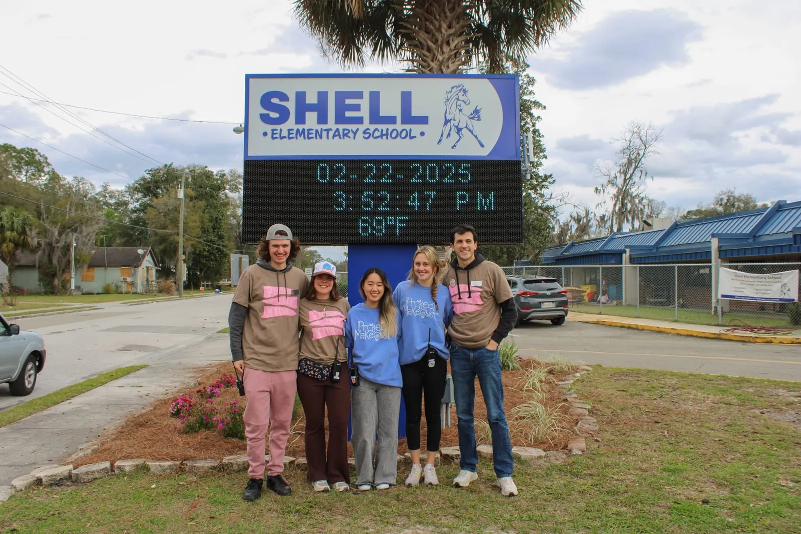Volunteers in Project Makeover shirts in front of the Shell Elementary School marquee